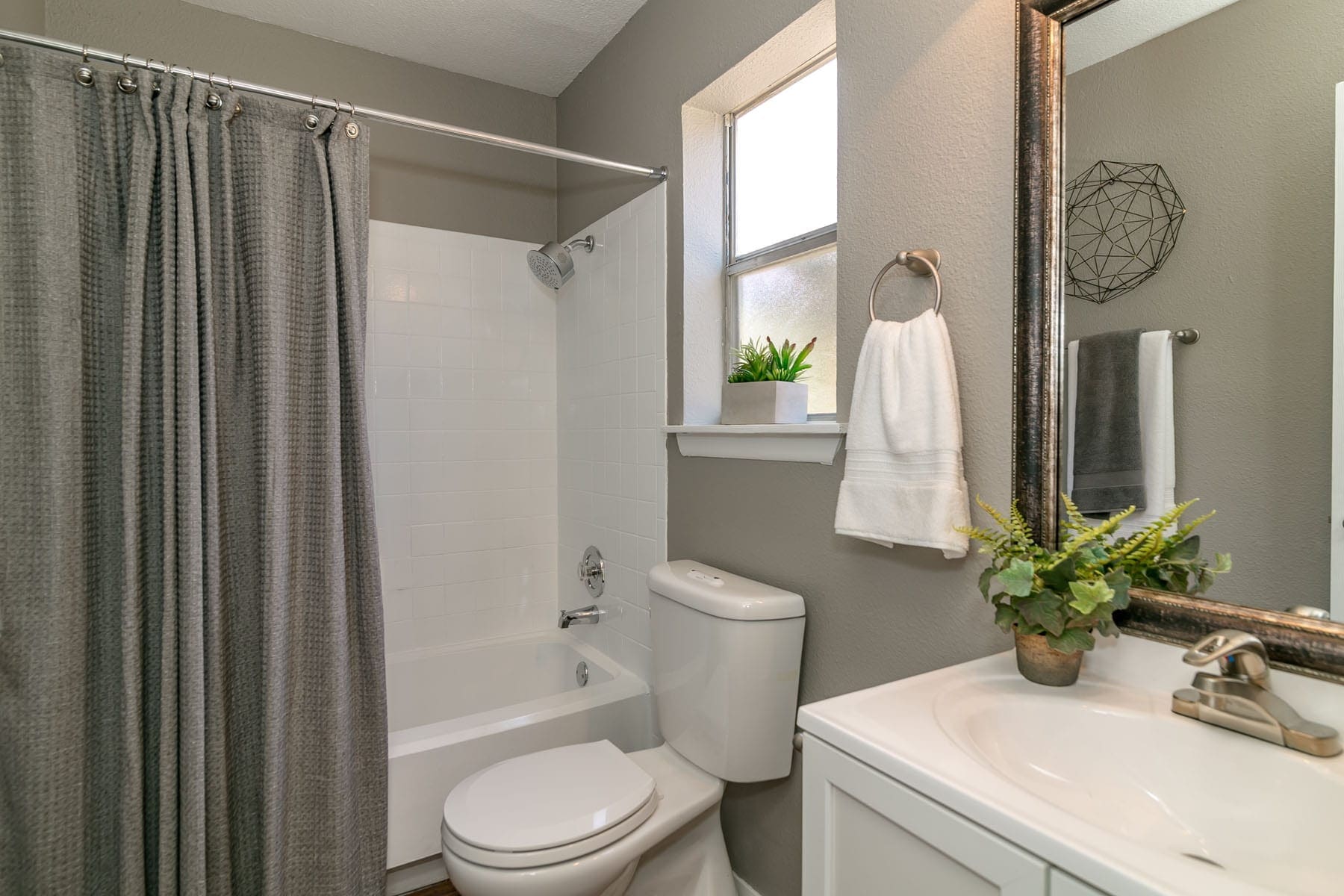 Apartments for Rent in San Antonio, TX - City-Base Vista - Bathroom with Grey Walls, Small Window, and Large Mirror
