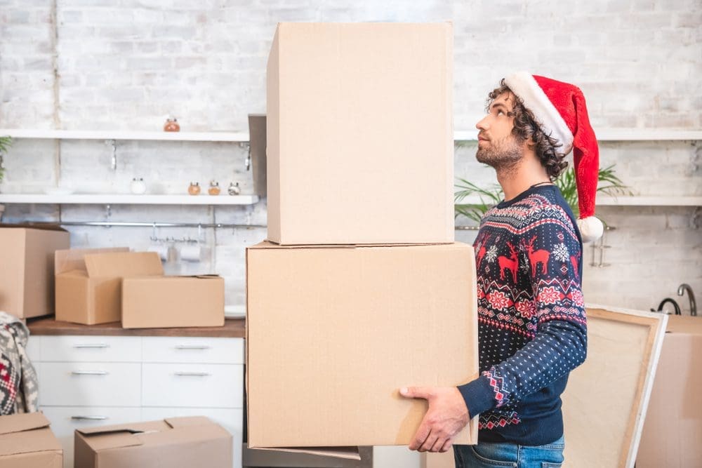 Side,View,Of,Young,Man,In,Santa,Hat,Holding,Cardboard