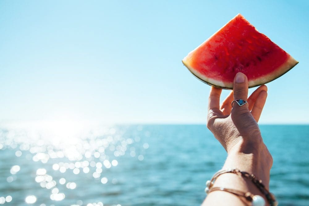 Watermelon,Slice,In,Woman,Hand,Over,Sea,-,Pov.,Summer